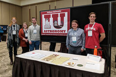 A group of students at a table with a sign that reads "IU Astronomy."
